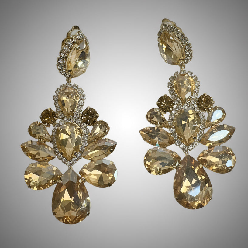 Pair of gold earrings with clear stones on a gray background