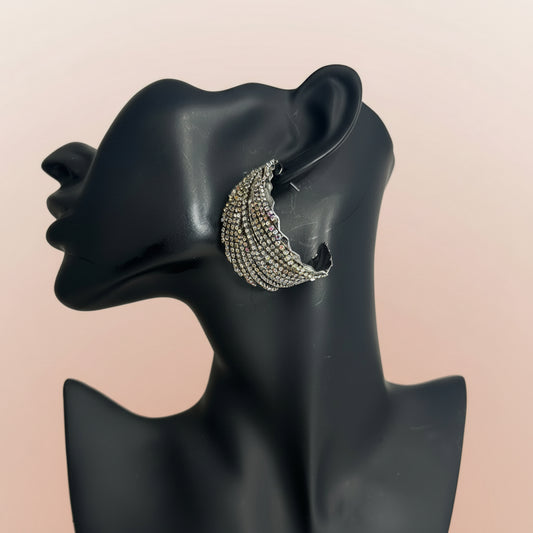 Silver rhinestone crescent moon earring on a black mannequin ear against a beige background.