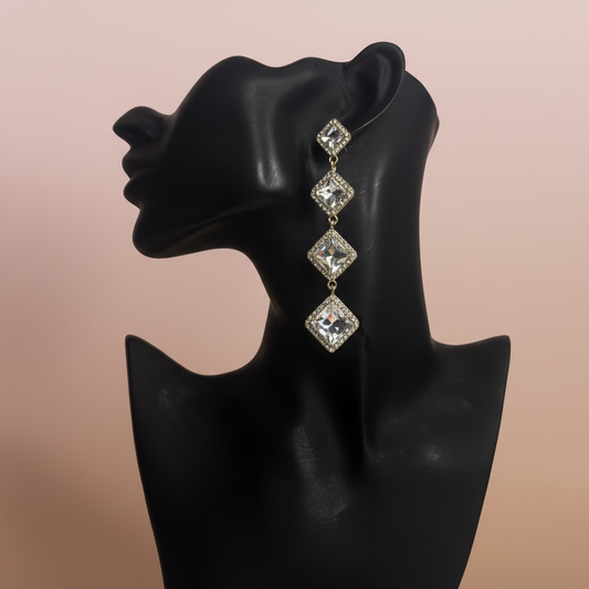 Diamond-shaped earrings on a black mannequin bust against a beige background