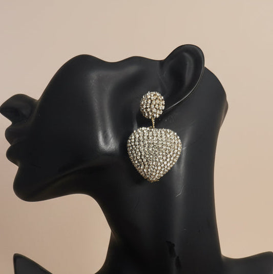 Heart-shaped earrings with rhinestones on a black mannequin ear