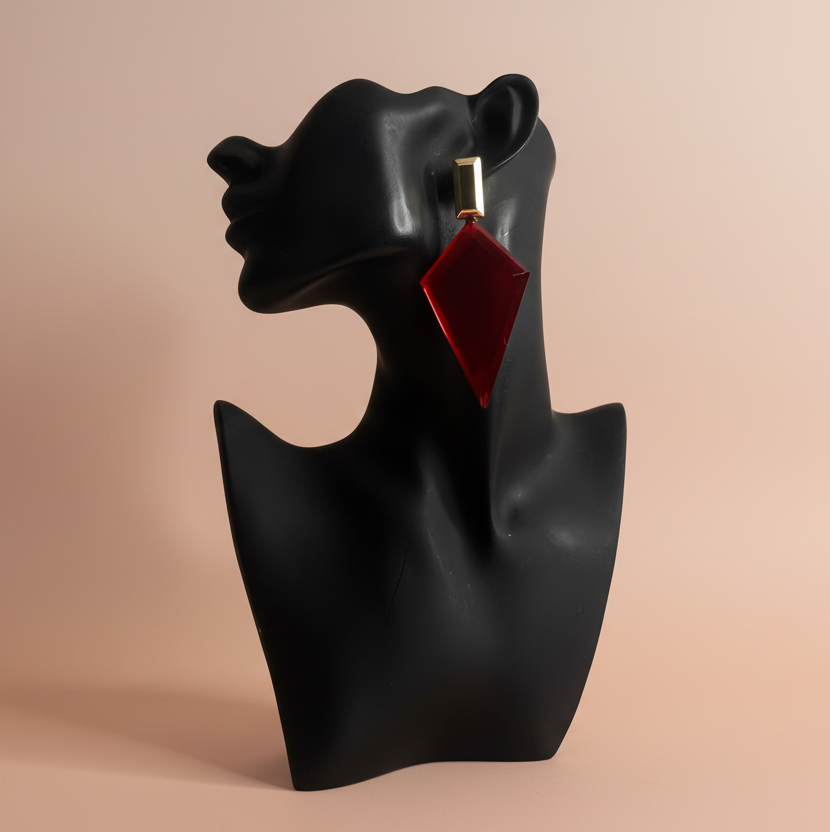 Red diamond-shaped earring on a black bust against a beige background