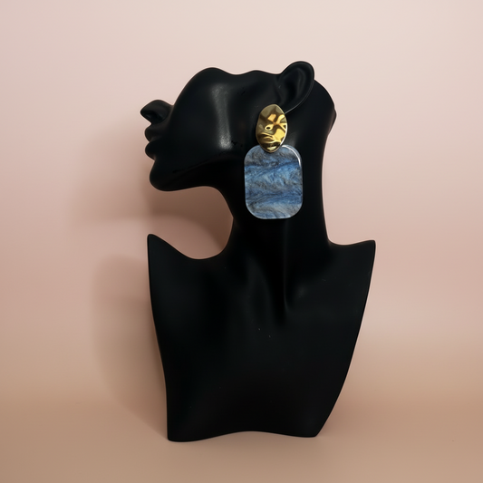 blue and gold square earring on a black mannequin with a beige background