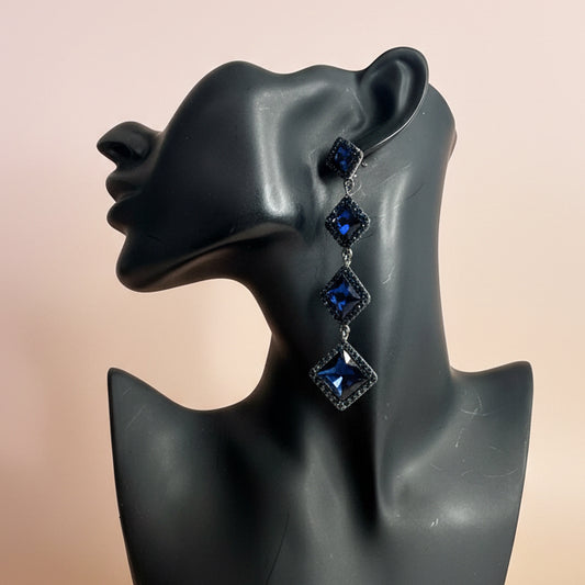 mannequin bust wearing blue gemstones earrings against a beige background