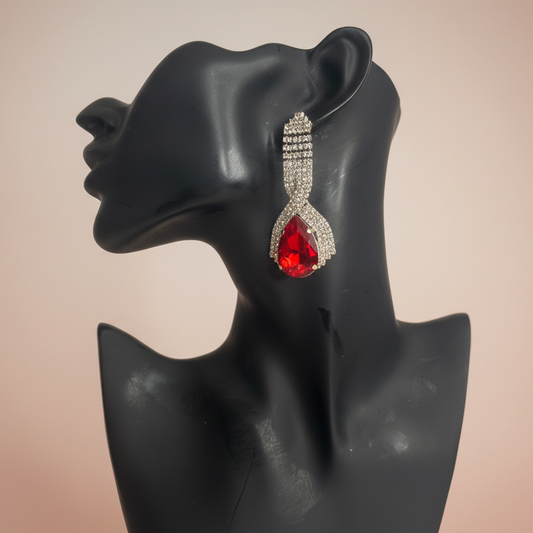 Red teardrop earring on a black mannequin head against a beige background