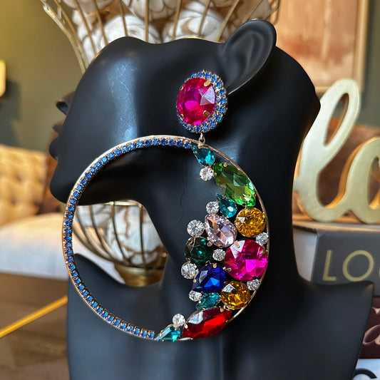 Multicolored large gemstone earring on a black mannequin ear with a blurred background