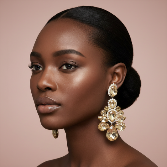 Woman wearing large, rose gold rhinestone ornate earrings against a soft pink background