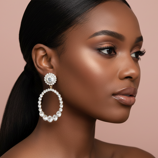 Woman wearing a  round, rhinestone  earring against a beige background