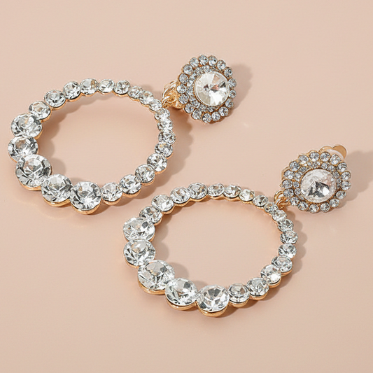 Pair of circle earrings with clear gemstones on a beige background