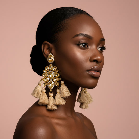 Woman wearing large, ornate gold earrings with tassels against a pink background