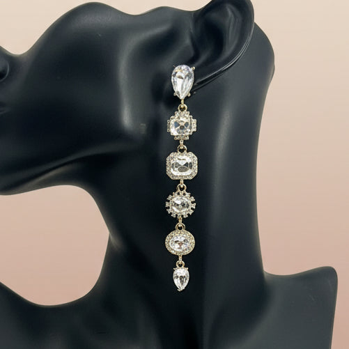 Dramatic crystal earrings on a black mannequin ear with a beige background