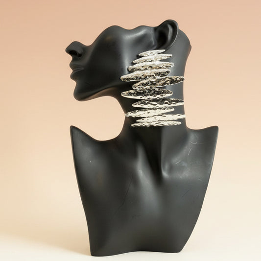 Silver cascading statement earrings displayed on a matte black mannequin bust against a neutral  background
