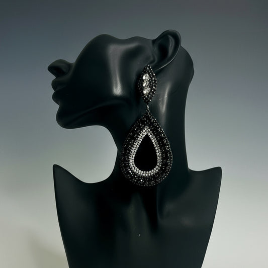 Black teardrop earring on a black mannequin ear against a gray background