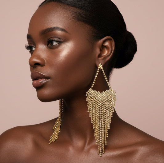 Woman wearing fringe gold earrings against a beige background