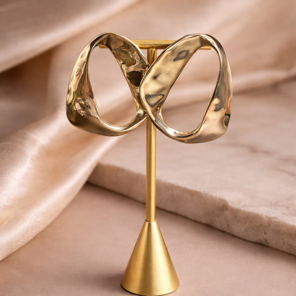 Gold earrings on a stand with a soft beige background