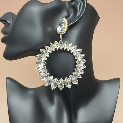 Earring displayed on a black mannequin ear against a blush wall background