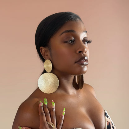 Woman wearing large gold circle earrings against a beige background