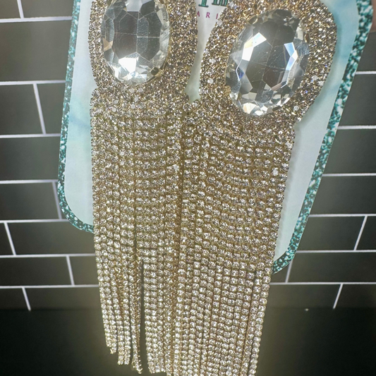 Rhinestone dangle fringe earrings with crystals  on a tiled wall background