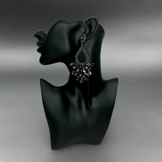 black rhinestone teardrop earrings on black mannequin against grayish black background