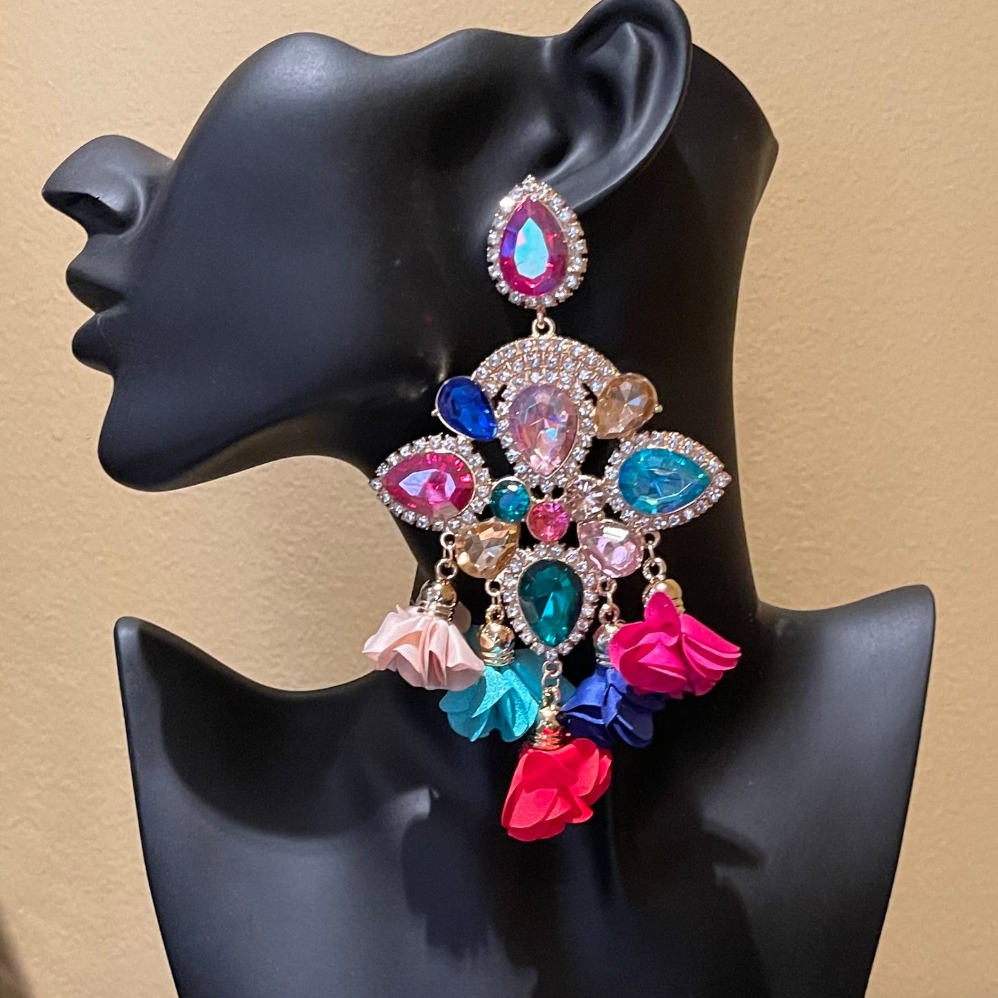 Colorful earrings on a black mannequin bust against a beige background