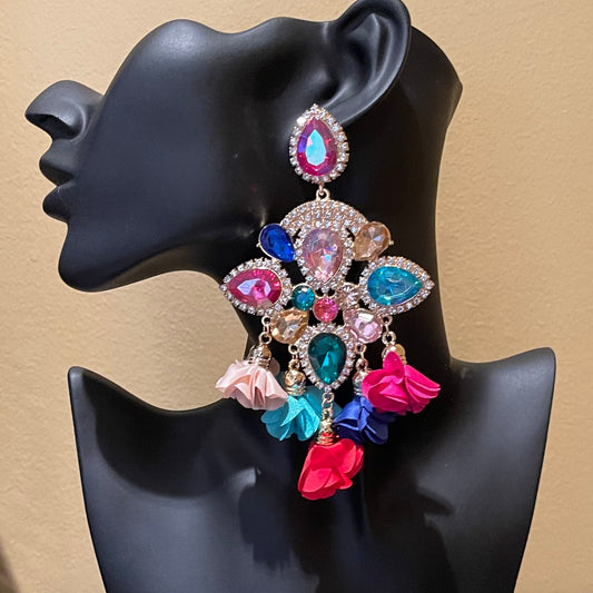 Colorful earrings on a black mannequin bust against a beige background