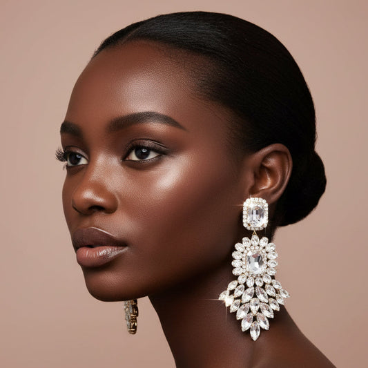 Woman wearing large, ornate rhinestone earrings against a neutral background