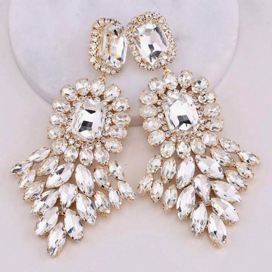 Pair of ornate rhinestone earrings with clear gemstones on a light background